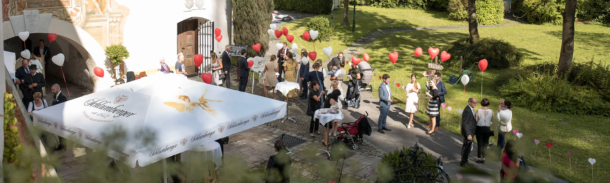 Hochzeitsgesellschaft im Schlosshof mit Herzballons
